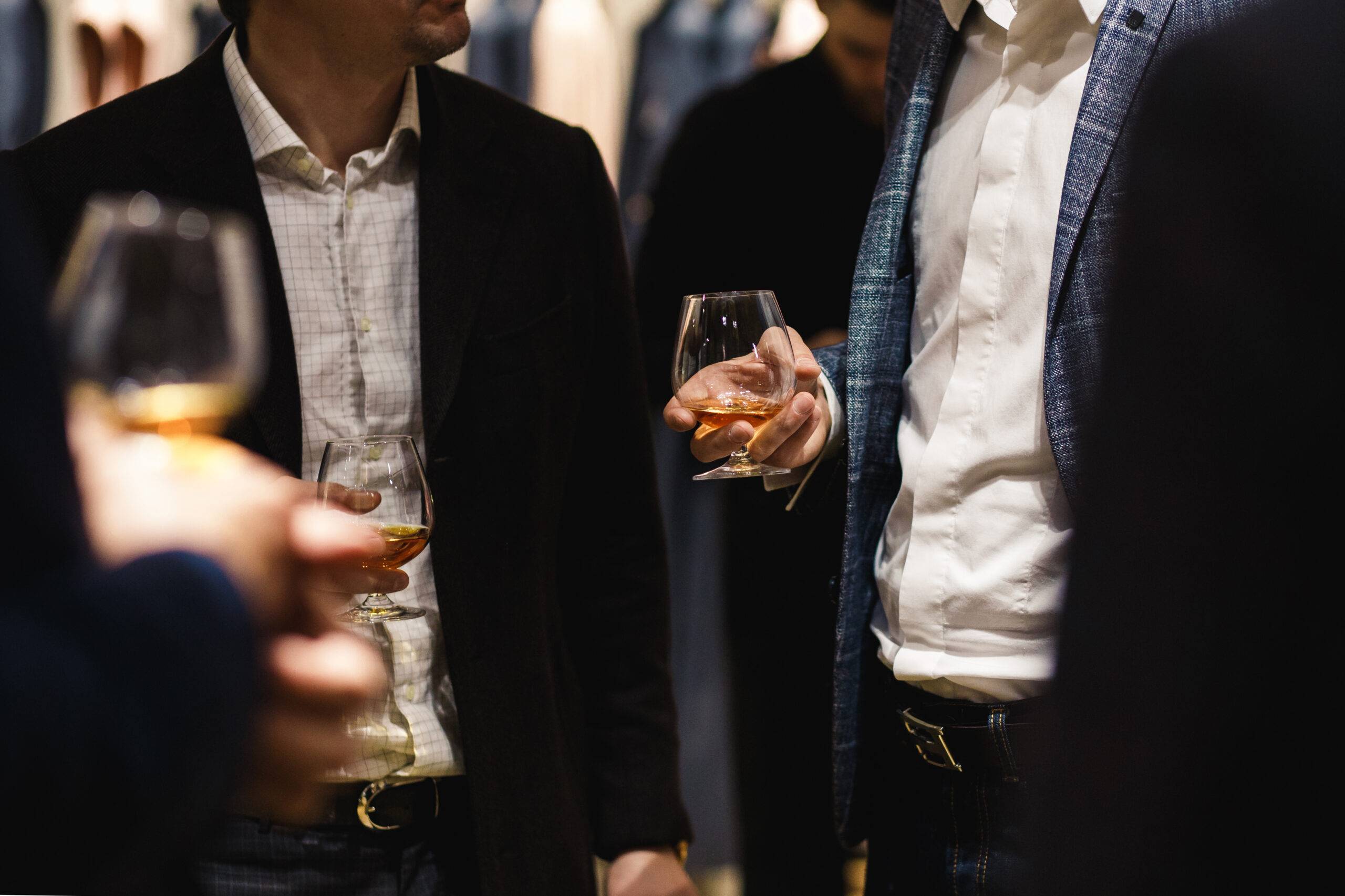 People standing chatting at a bussiness dinner holding whisky and wine glass tasting and degustating food chef's food